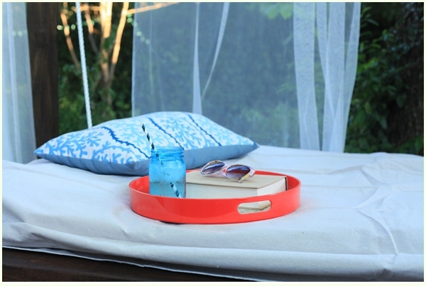 Outdoor swing bed with book and drink on a tray