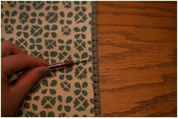 A seam ripper being used to create a small opening in the seam of a placemat.