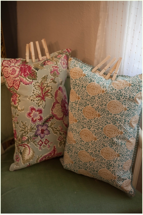 Two DIY pillows with floral designs with the seams clothes-pinned together for drying.