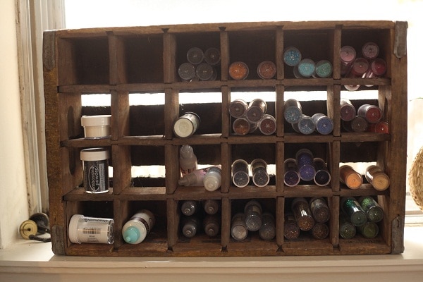 A thrifted wooden organizer filled with various craft supplies. 