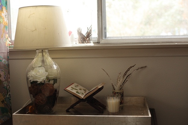 Decorative tray with a lamp, plant, candle and bookstand inside. 
