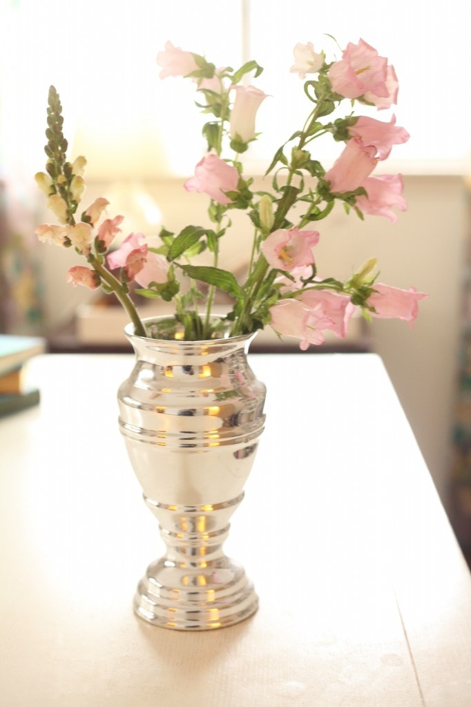 A silver vase with fresh, pink flowers inside. 