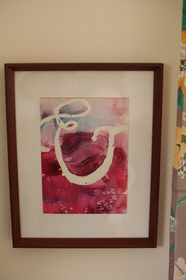 A watercolor painting in a brown wooden frame. 