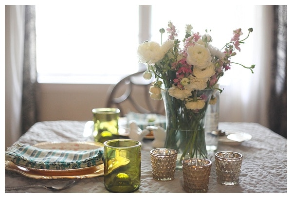 A kitchen table set with dishes and a vase of fresh flowers. 