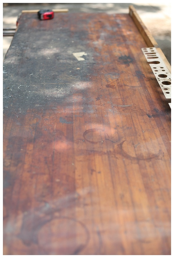 Close up of the dirty and stained wood top of an old work table. 