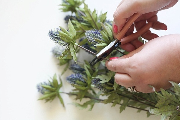 Using wire cutters to trim fake purple flowers 
