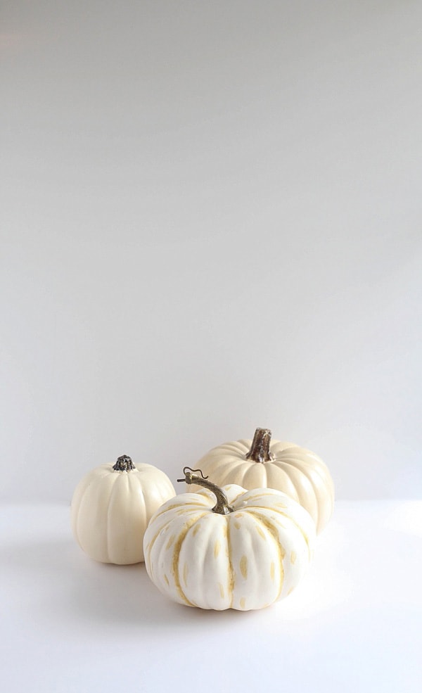 Three faux pumpkins on a white tabletop.