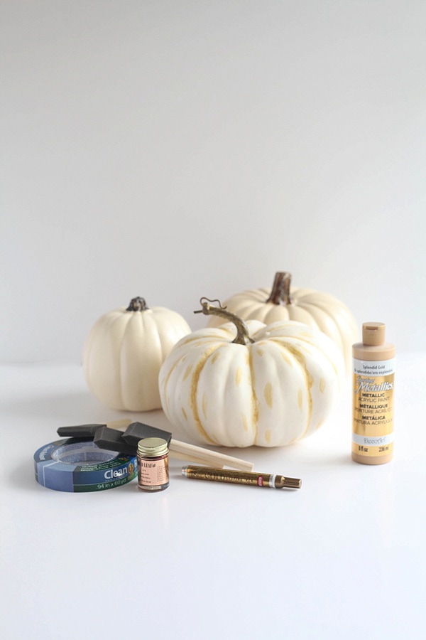 Gold leaf pumpkin DIY supplies including metallic paint, foam brushes, gold leaf and painters tape. 