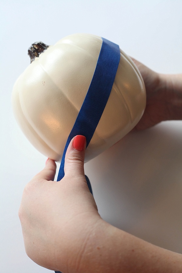 Taping a plastic craft pumpkin with painter's tape.