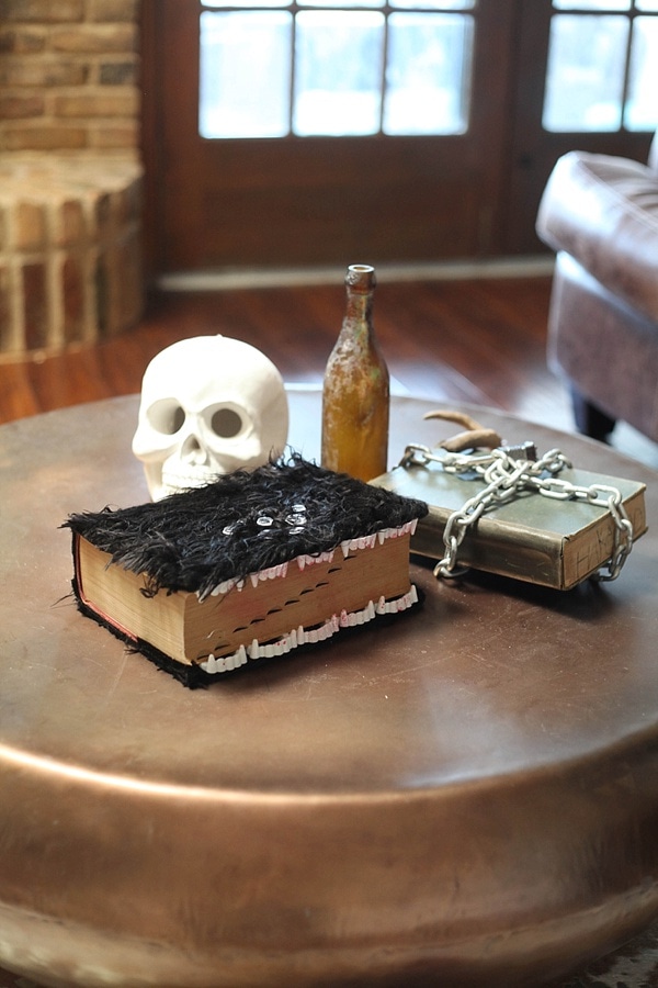 coffee table covered in a skull, wine bottle, and Halloween books as Halloween decoration ideas