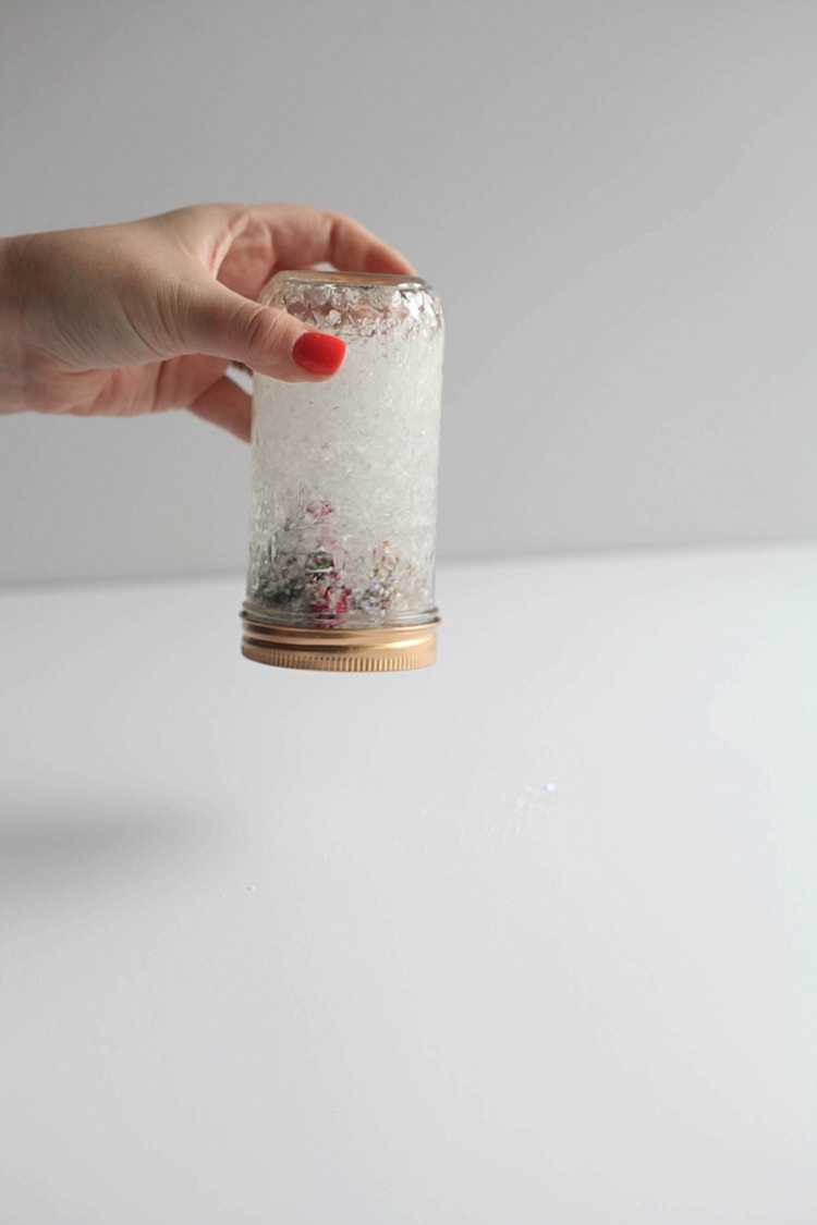 Mid shake of snow globe in a mason jar