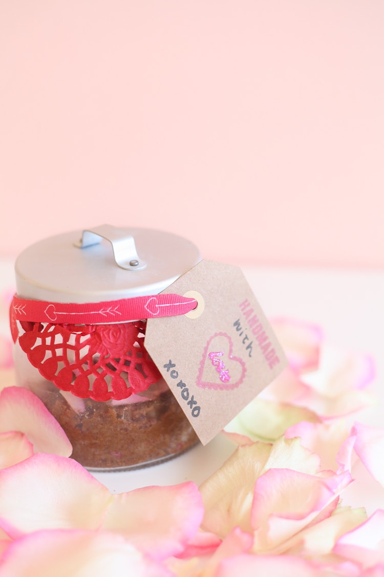 DIY sugar scrub in a glass jar with rose petals around it