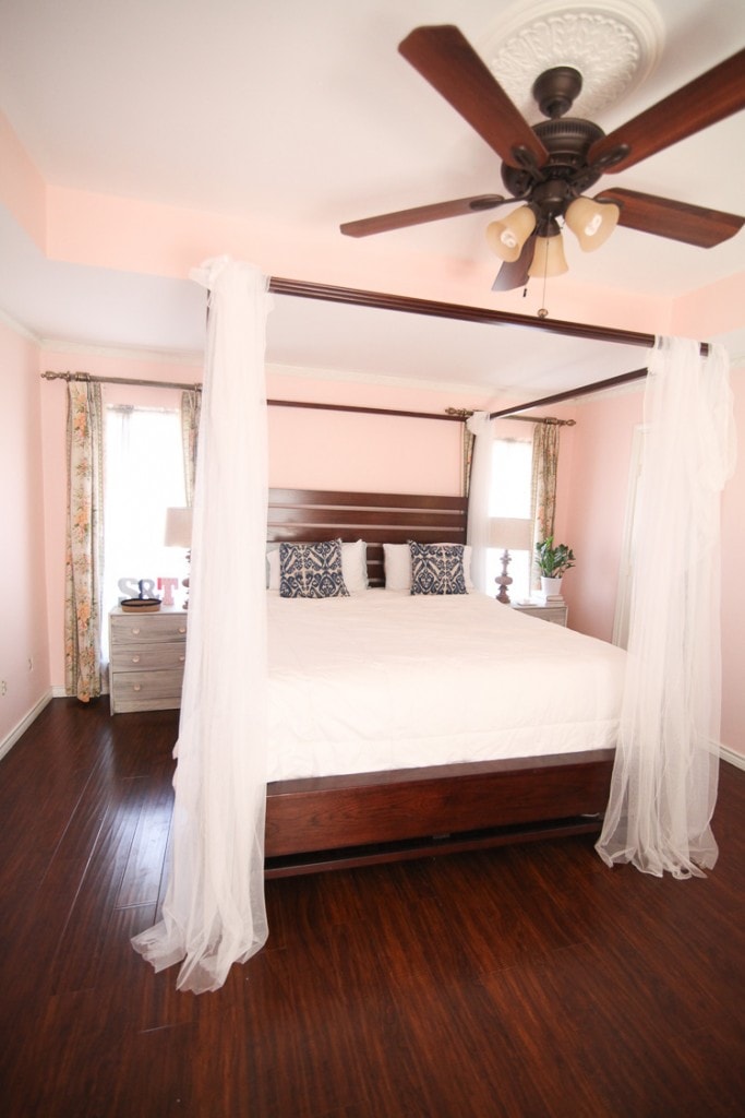 pink bedroom with canopy bed and ceiling fan just above