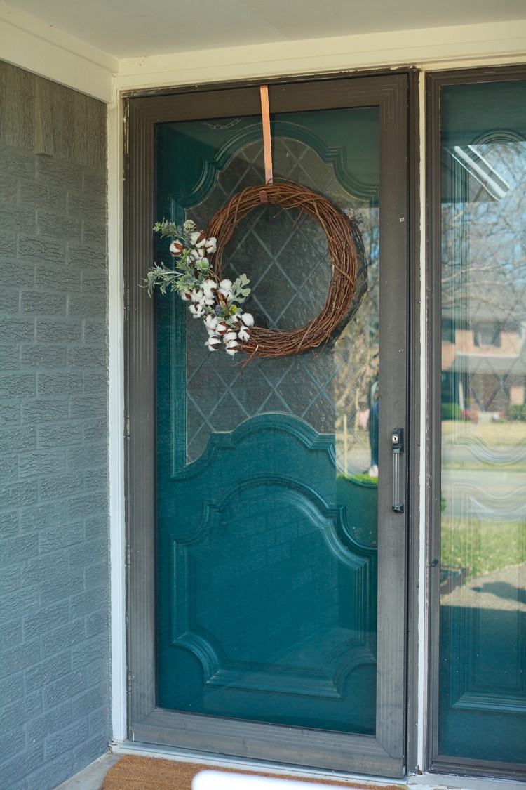 Front door painted teal with a lovely wreath hanging on it