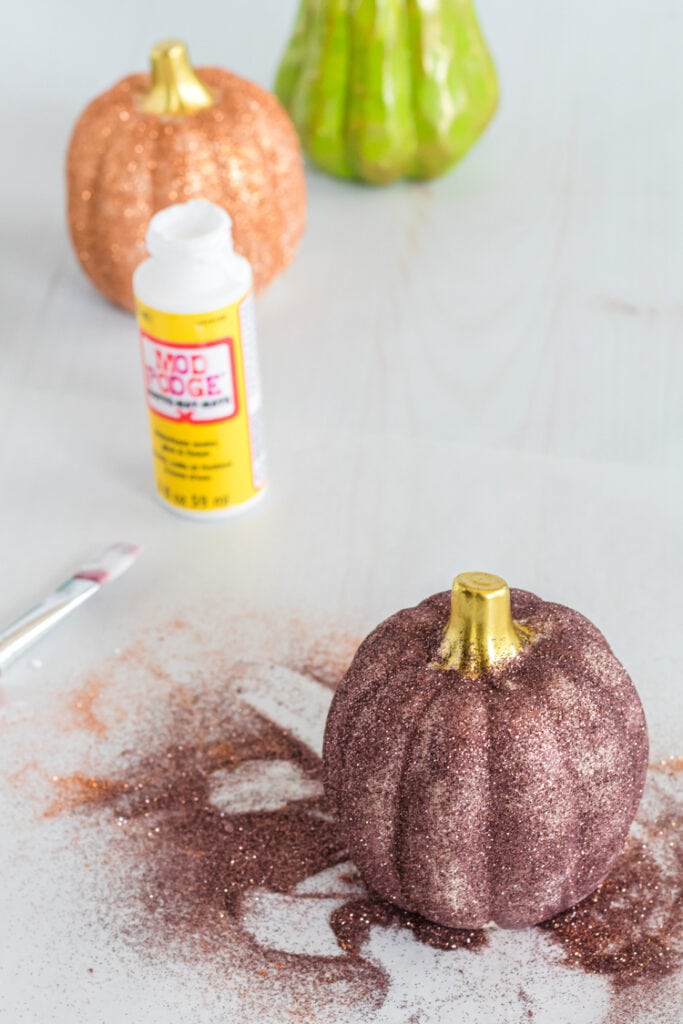 Pumpkins with glitter being made on a table top.