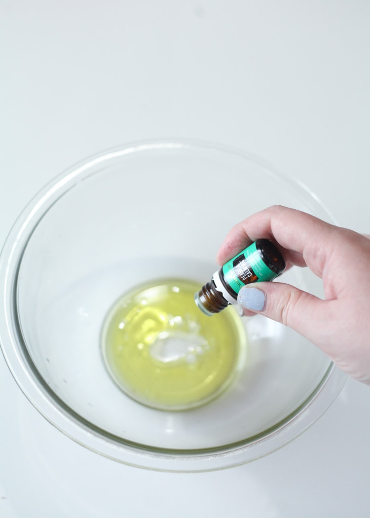 pouring essential oils into a bowl of wet ingredients for the DIY bath bomb recipe