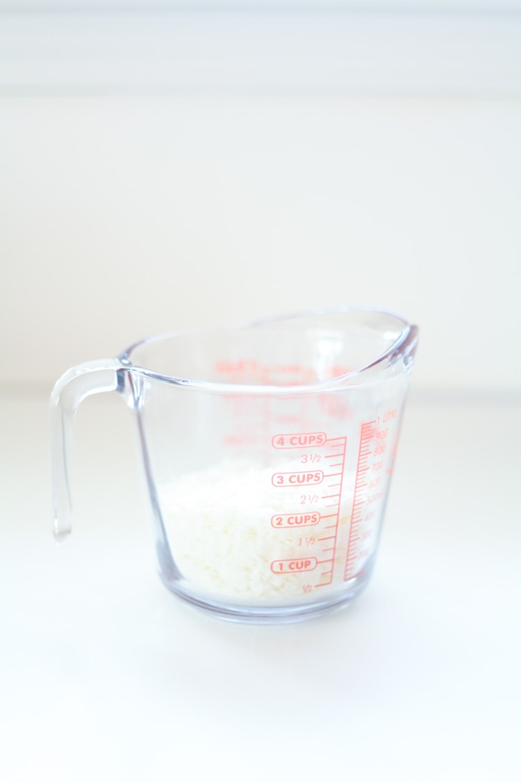 Glass measuring cup with unmelted soy wax inside. 