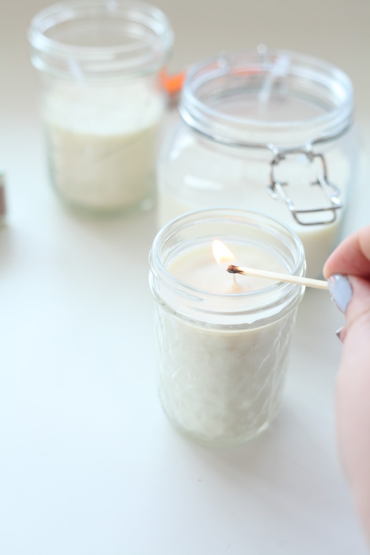 Using a match to light the wick of a diy candle made with essential oils.