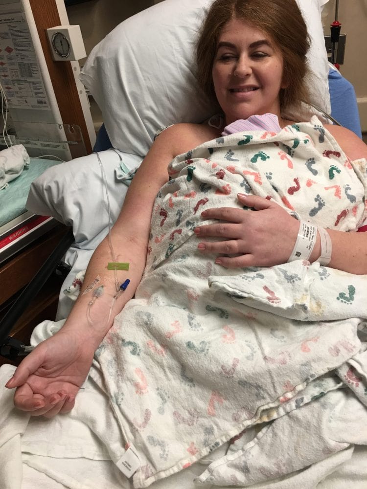 Woman with IV in arm doing skin to skin with baby after delivery