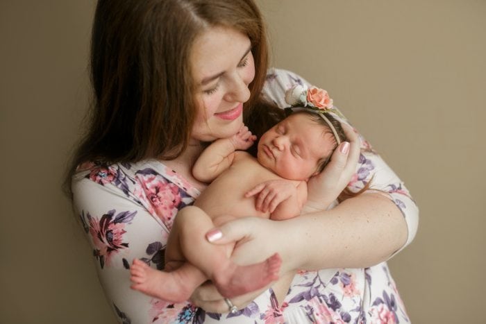 Picture of a mother in a floral dress holding a newborn baby