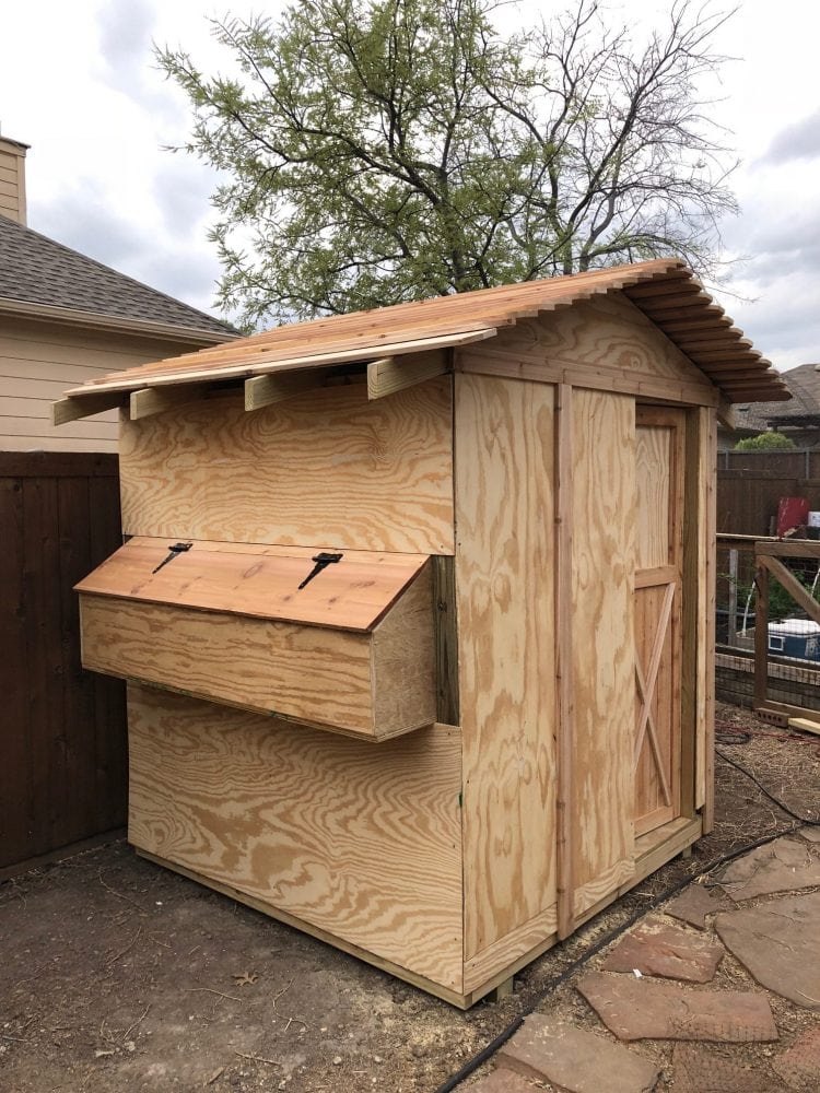 wooden unpainted chicken coop with nesting box and country style door