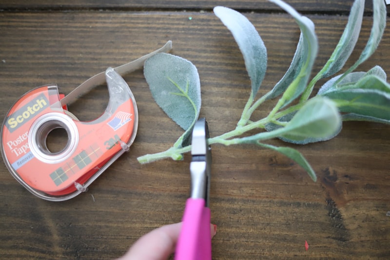 pink scissors cutting a faux greenery stem