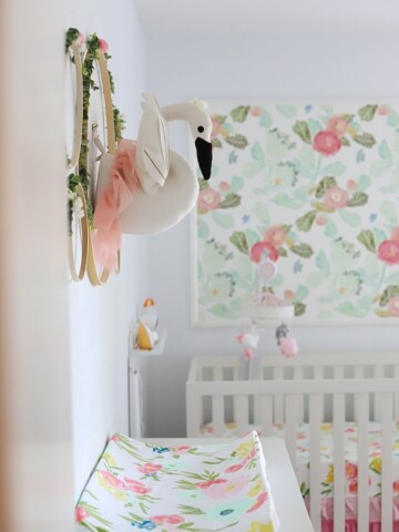DIY nursery wall decor with flowers and a swan in a baby girl nursery with floral wallpaper in background