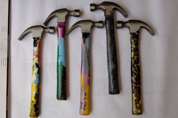 5 hammers laid on a table with painted handles
