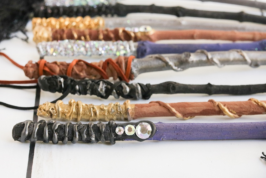 Row of diy harry potter wands in purple, black, brown, gold and silver