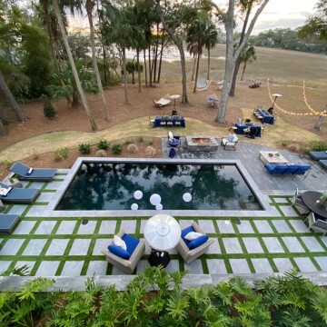 Overhead shot of swimming pool with pavers and turf, with ocean in background