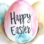 Watercolor egg close up with words "Happy Easter" hand written with paint marker