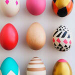 wooden easter eggs painted and laid out evenly spaced on a countertop