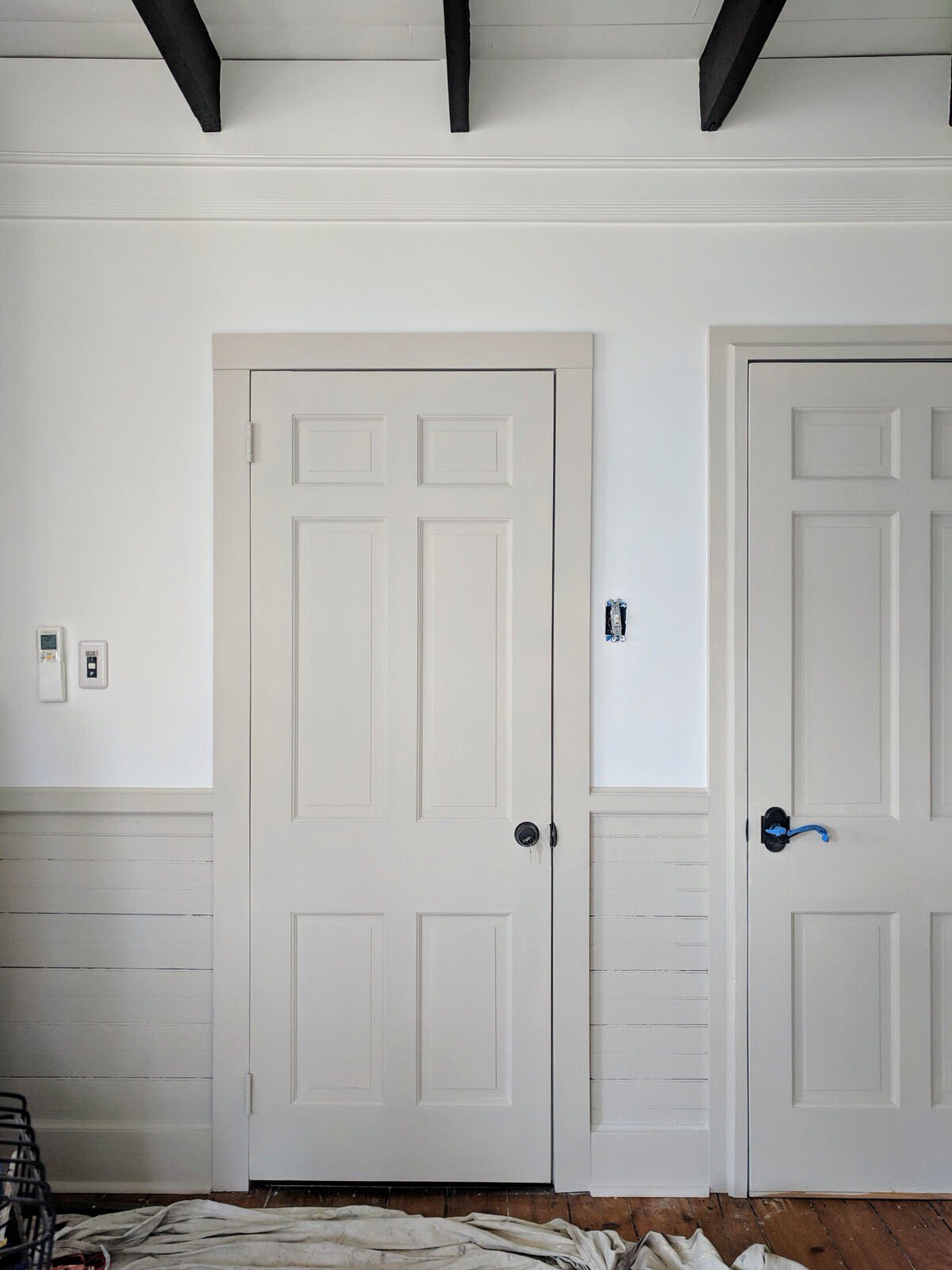 Hallway and interior doors with white walls and wainscotting and trim Baby Fawn by Benjamin Moore.