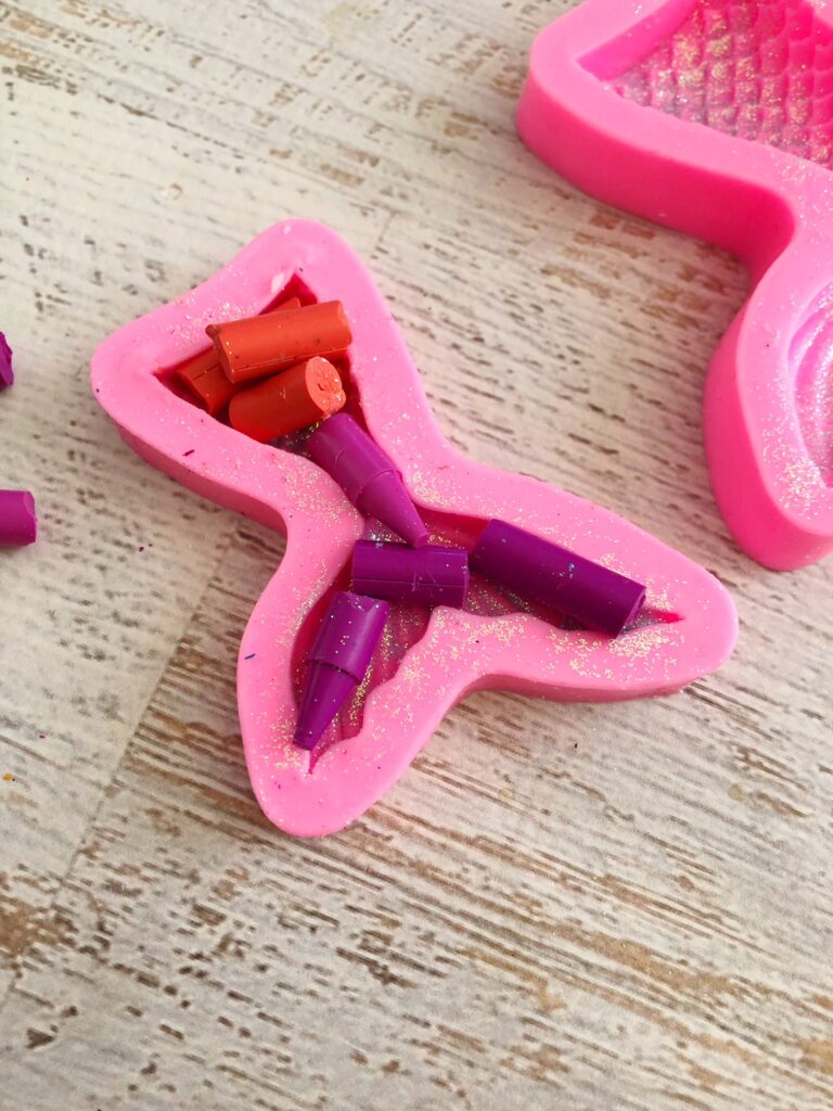 Purple and red crayons in a mermaid tail mold 