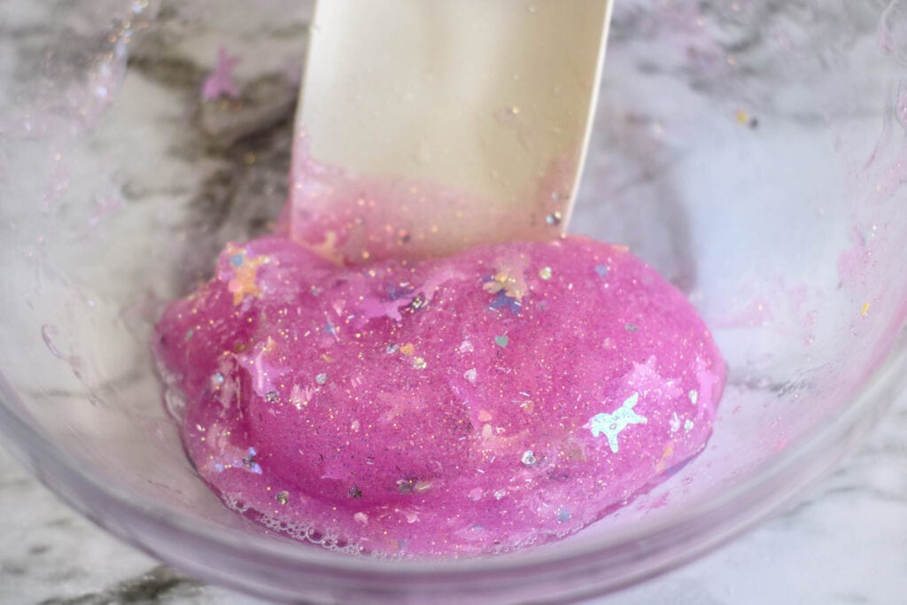 After mixing in contact lens solution, the DIY unicorn slime will start to form a soft ball.