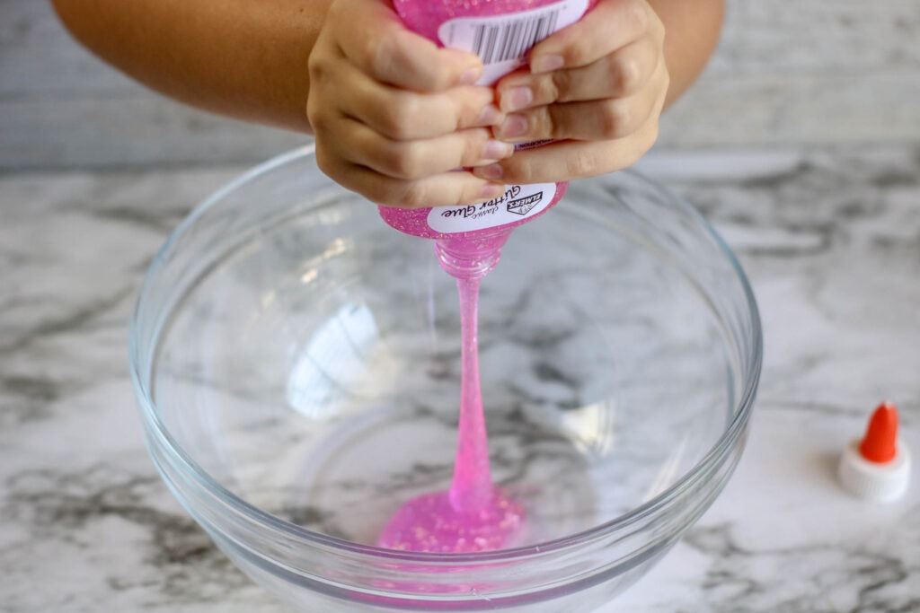 Emptying Elmer's pink glitter glue into a bowl to make DIY unicorn slime.