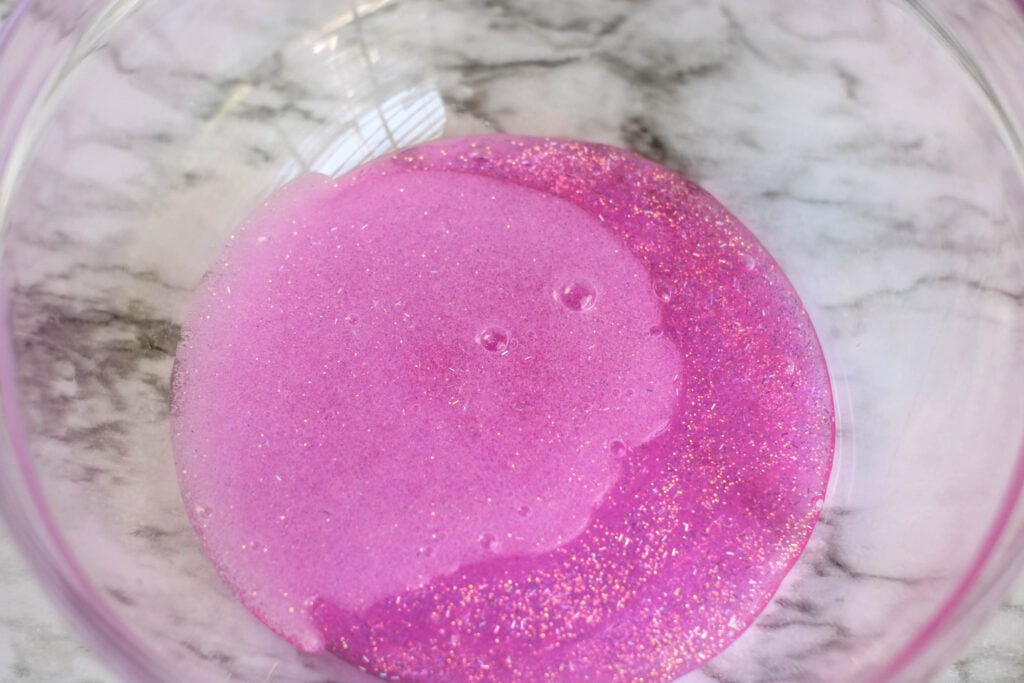Bowl of Elmer's pink glitter glue with warm water added to make DIY unicorn slime.