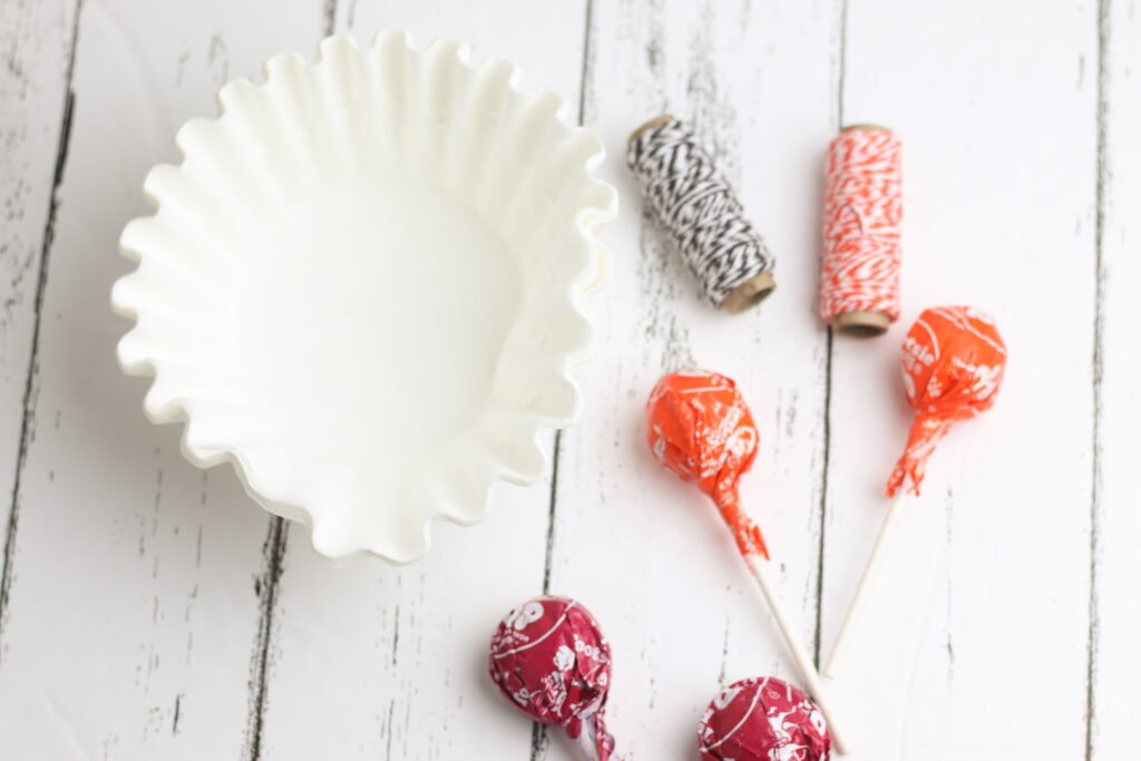 Supplies needed to make ghost lollipops: Tootsie Pops, coffee filters, twine and black marker.