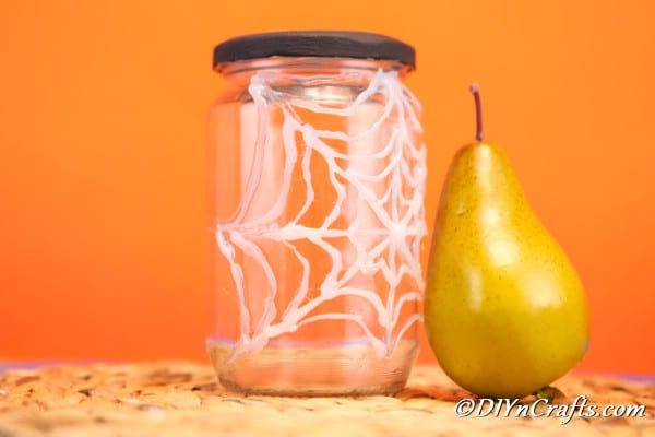 DIY Halloween decoration ideas: spider web jar styled with a faux pear.