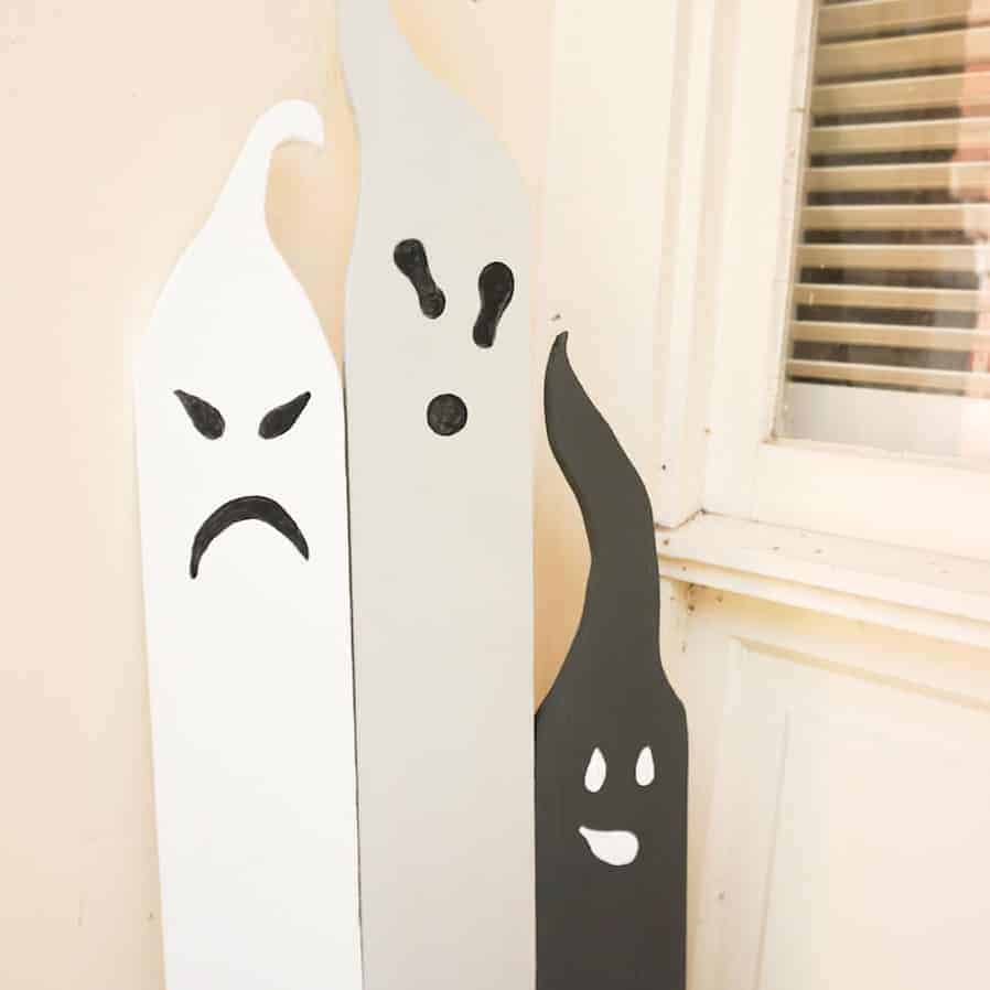 Painted wooden ghosts for outdoor DIY Halloween decor.