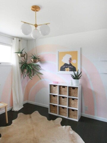 Pink rainbow painted on a white wall in a bedroom.