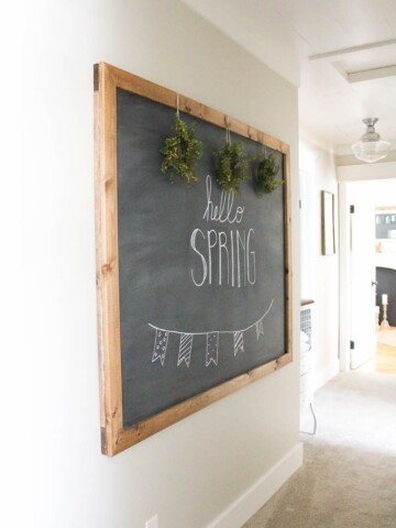 Chalkboard that reads Hello Spring hanging on a white wall.