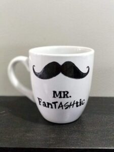 White coffee mug with a mustache drawn on it that reads mr. fantashtic.
