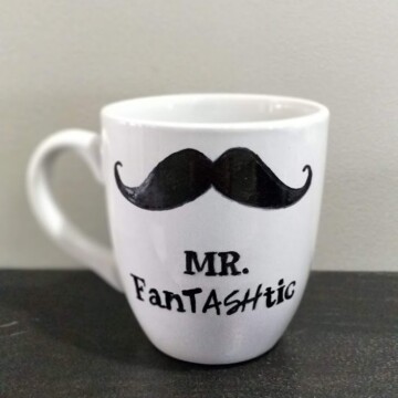 White coffee mug with a mustache drawn on it that reads mr. fantashtic.