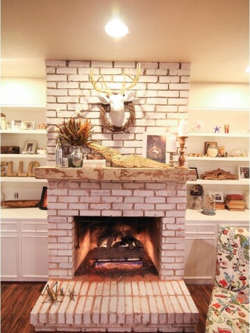 Fireplace and mantel with fall decor including candles and deer head with grapevine wreath.