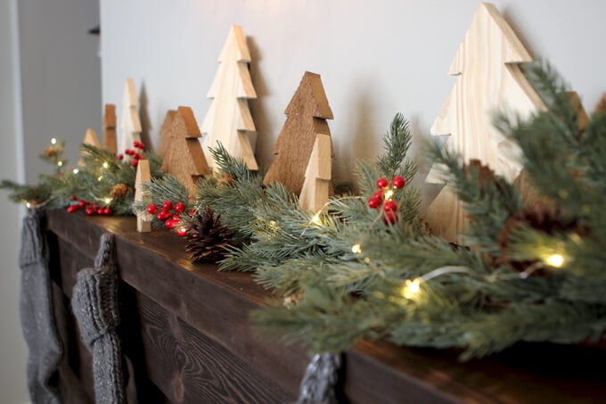 Wooden tree cutouts and garland on holiday mantel