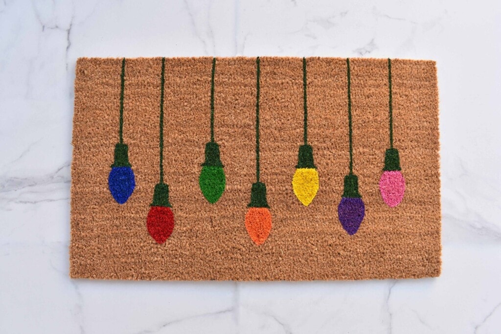 a natural colored doormat with hanging Christmas lights 