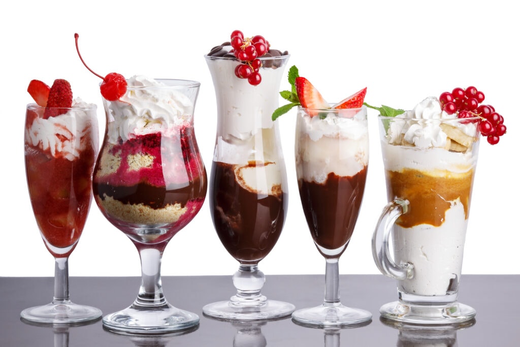 American parfait. Delicious layered desserts in elegant bar glasses decorated with fresh berries. Sweet food