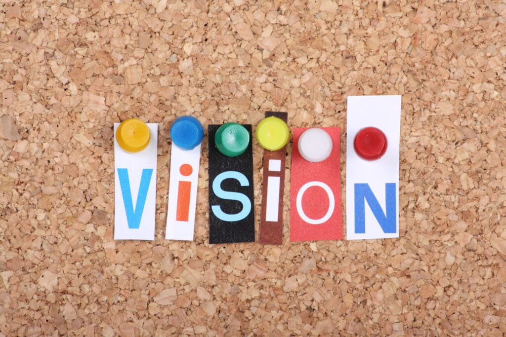 The word Vision in cut out magazine letters pinned to a cork notice board,