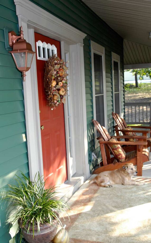 front porch with a painted door, hanging wreath, and chairs